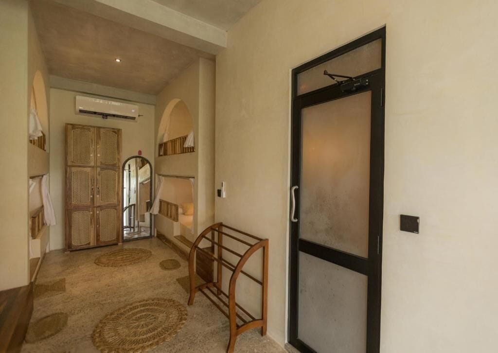 A hallway with a wooden bench, a glass door, and a ceiling-mounted air conditioner.
