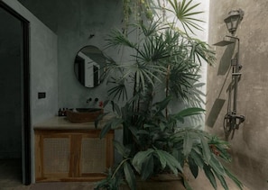 A bathroom with a wooden vanity, a round mirror, a potted plant, and a wall-mounted shower. - Roaming Retreat Hostel & villa (Ahangama)