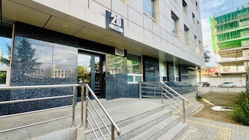 A building with a sign indicating the number 20, a set of stairs with metal railings, and a paved entrance area.