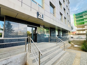 A building with a sign indicating the number 20, a set of stairs with metal railings, and a paved entrance area.