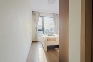A modern bedroom with a large window, a bed, and a view of a cityscape. - City views (Nairobi)