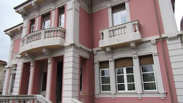 Un edificio con fachada rosa, detalles blancos y balcones ornamentados.