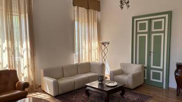 A living room with a beige sofa, a coffee table, a floor lamp, a patterned rug, and a green door.