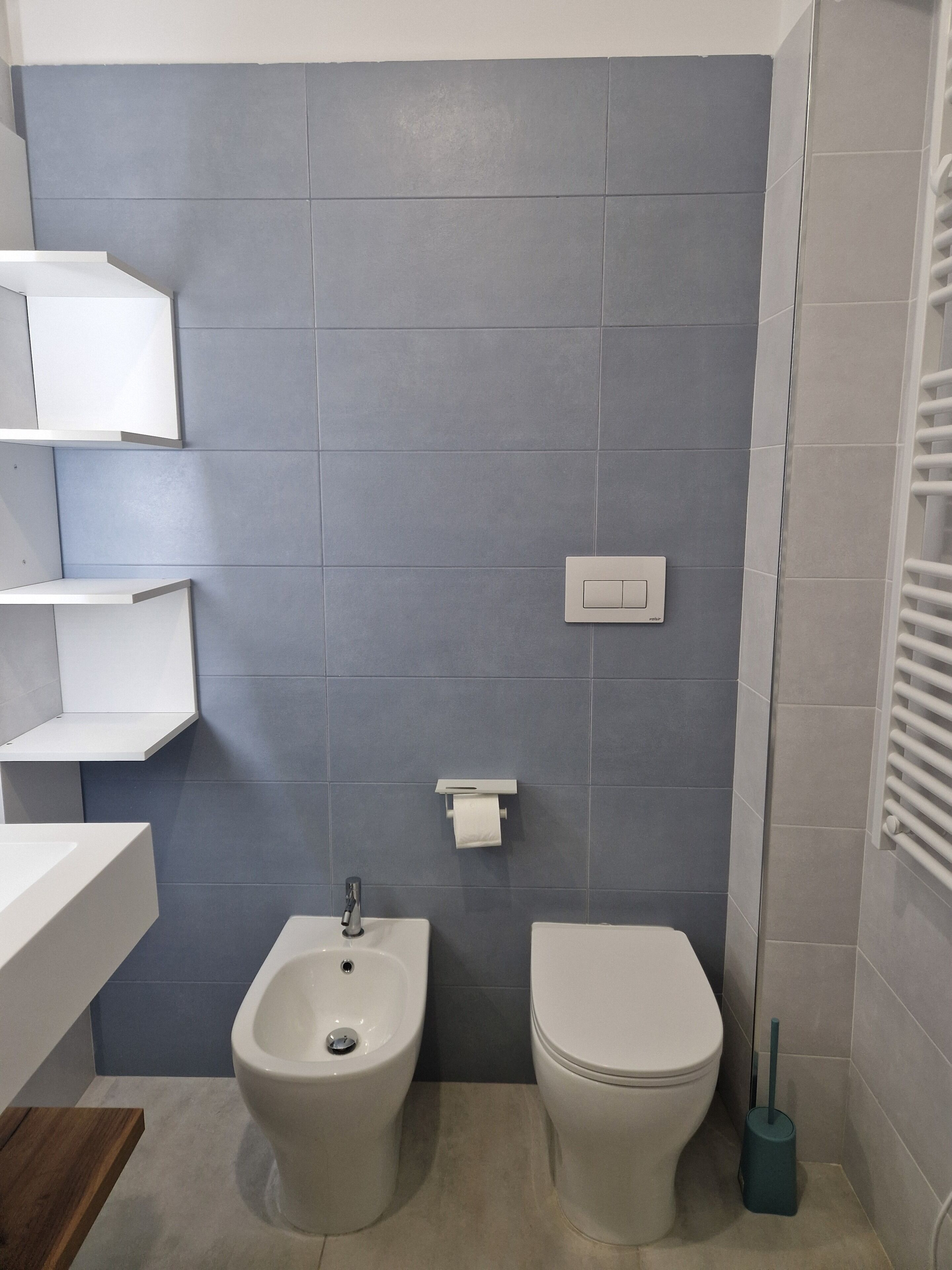 Un baño con bidé, inodoro y un perchero para toallas.