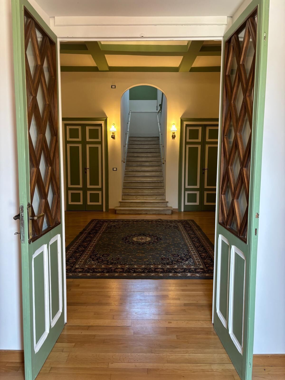 A staircase with a handrail, a carpet, and a door with a diamond-patterned design.