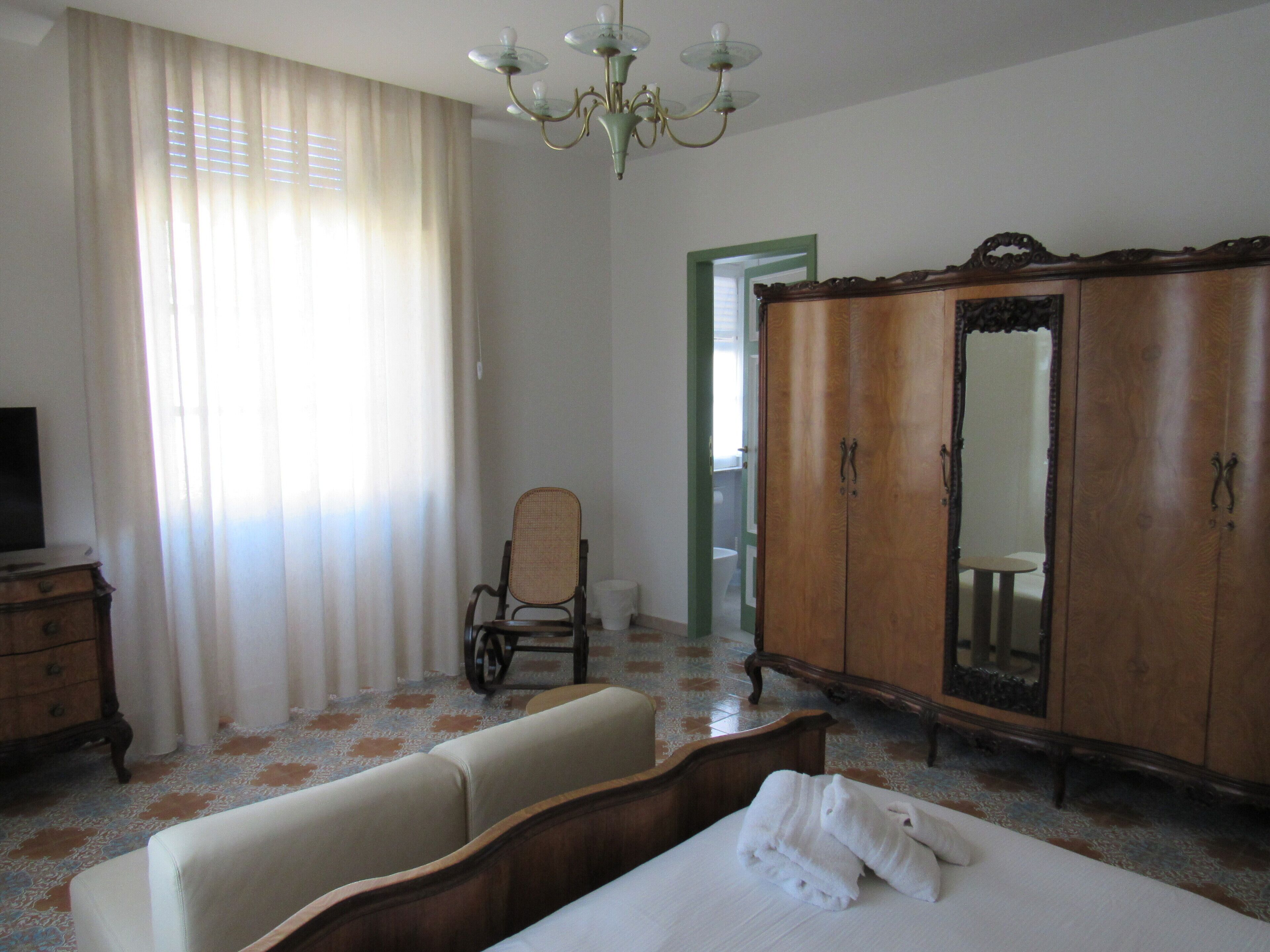 Una habitación con cama, armario de madera, silla y televisor.
