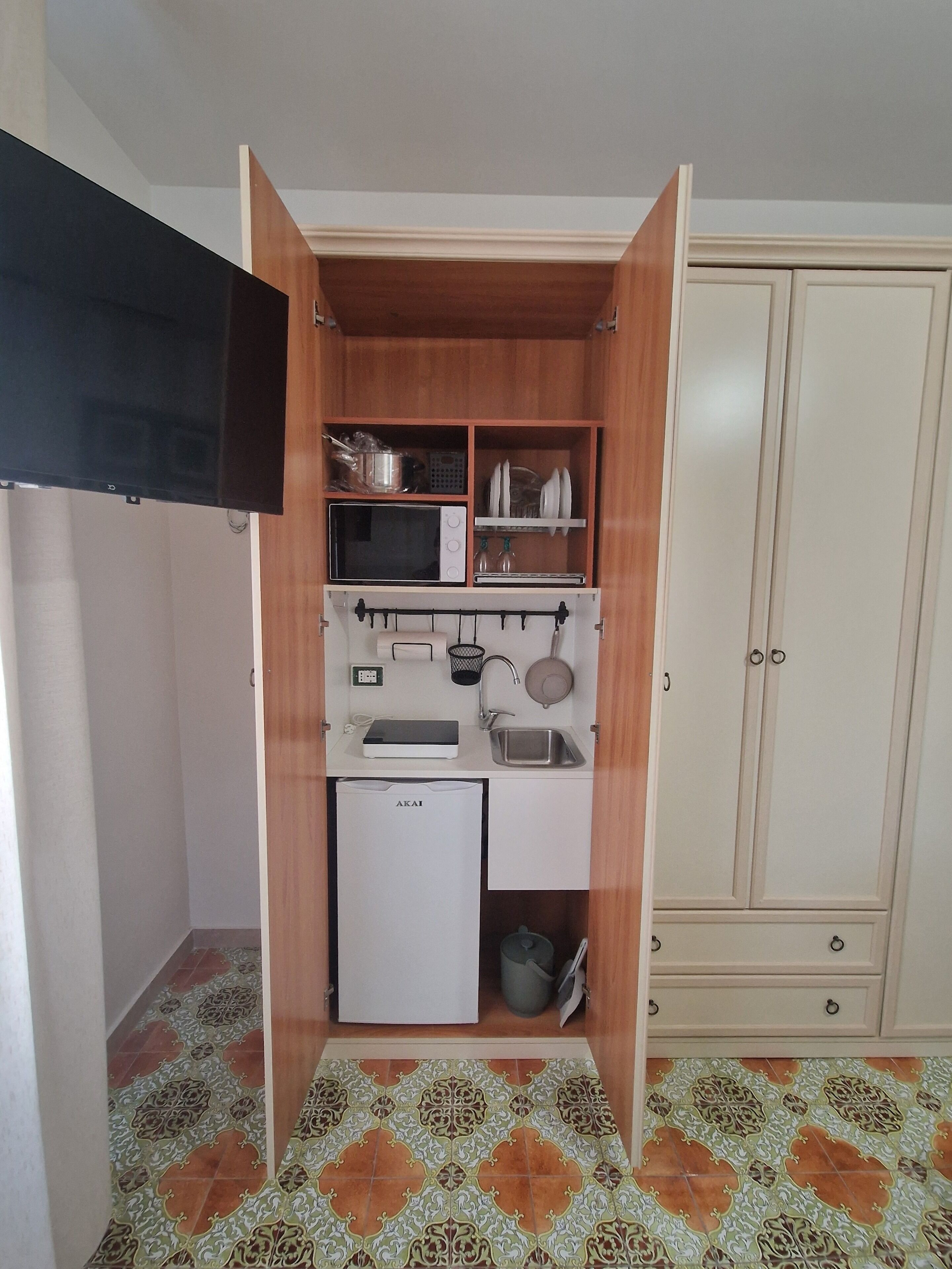 Una kitchenette compacta con microondas, pileta y alacenas.
