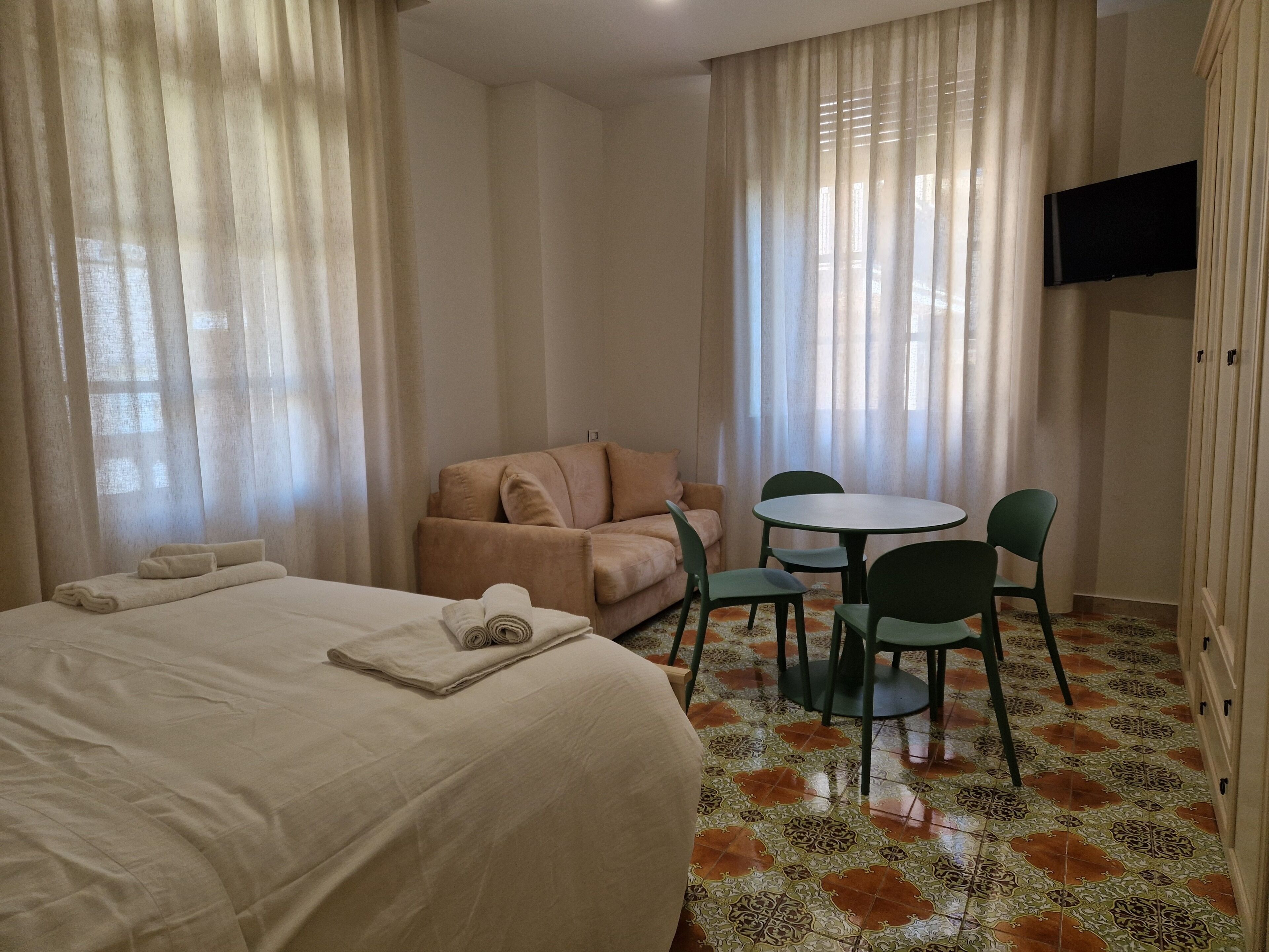 Una habitación de hotel con una cama, un sofá, una mesita redonda y sillas.