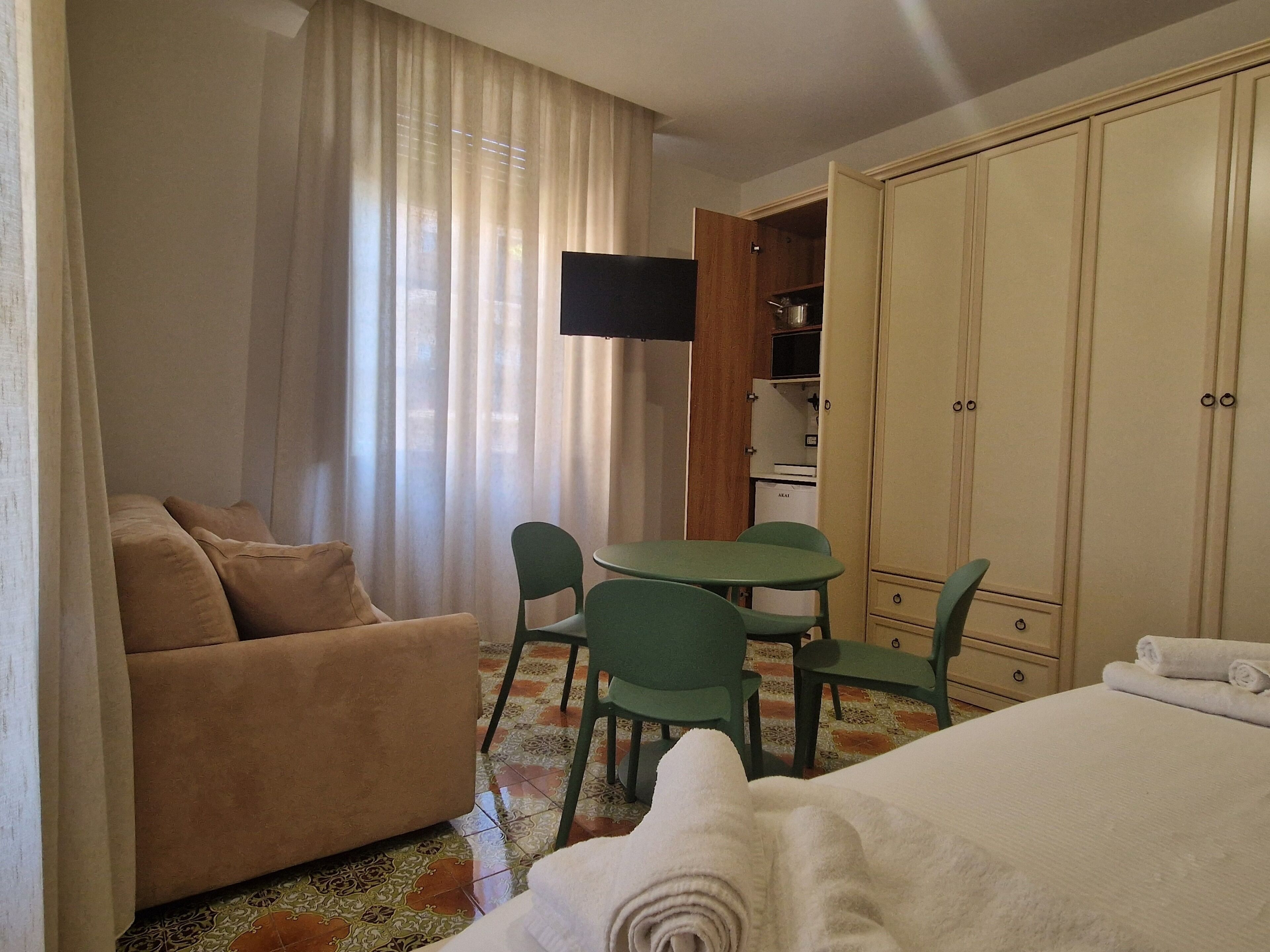 Une chambre d’hôtel avec un canapé, un lit, une petite table, une télévision et une armoire.