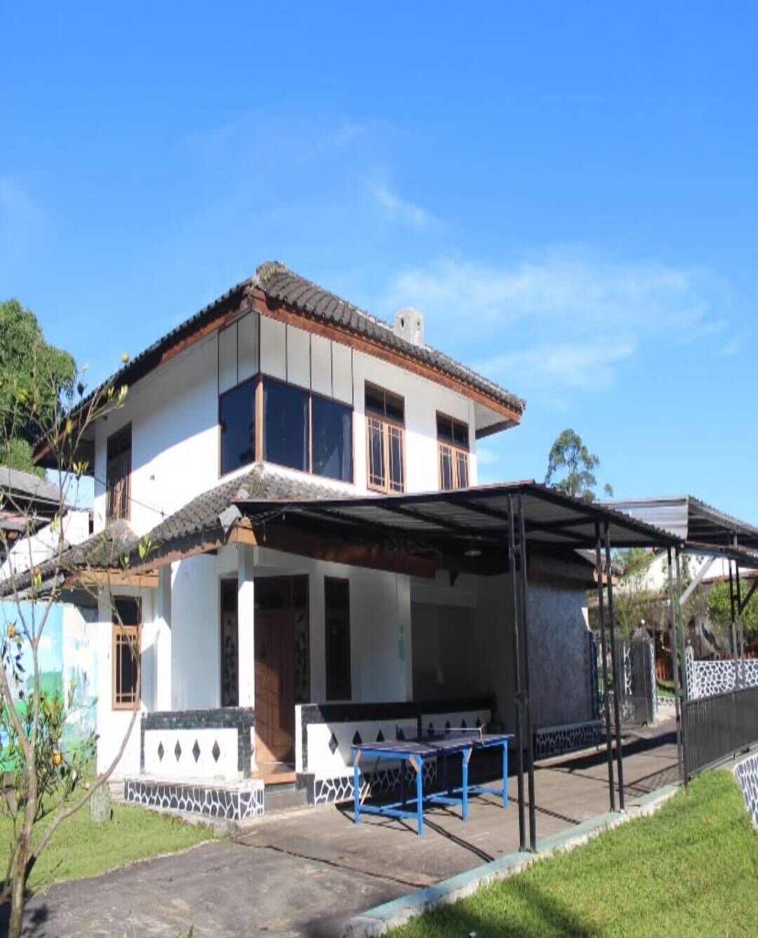 A two-story house with a covered porch and a blue table.