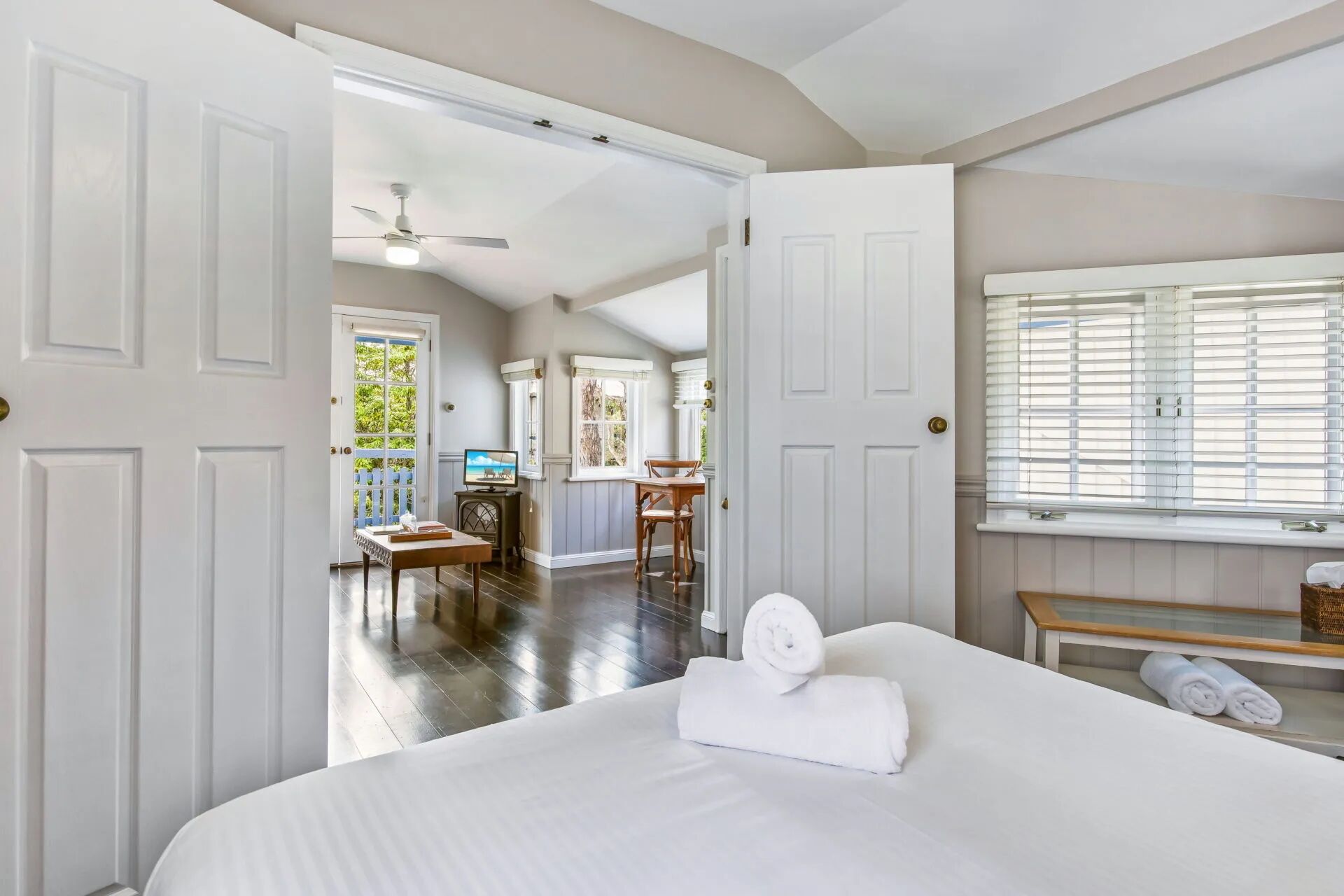 A hotel room with a bed, a desk, a chair, a television, and a window with blinds.