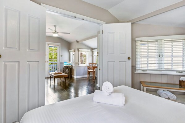 A hotel room with a bed, a desk, a chair, a television, and a window with blinds.