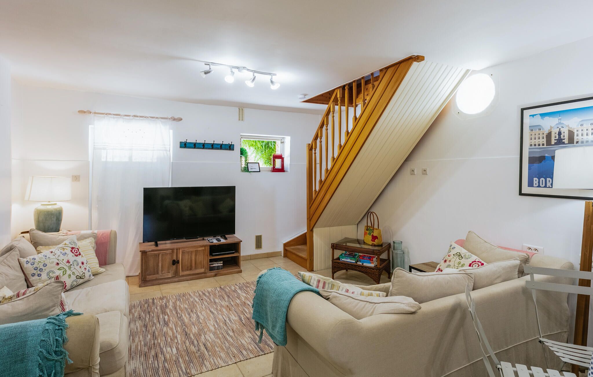 Un salon avec un téléviseur, un canapé et un escalier.