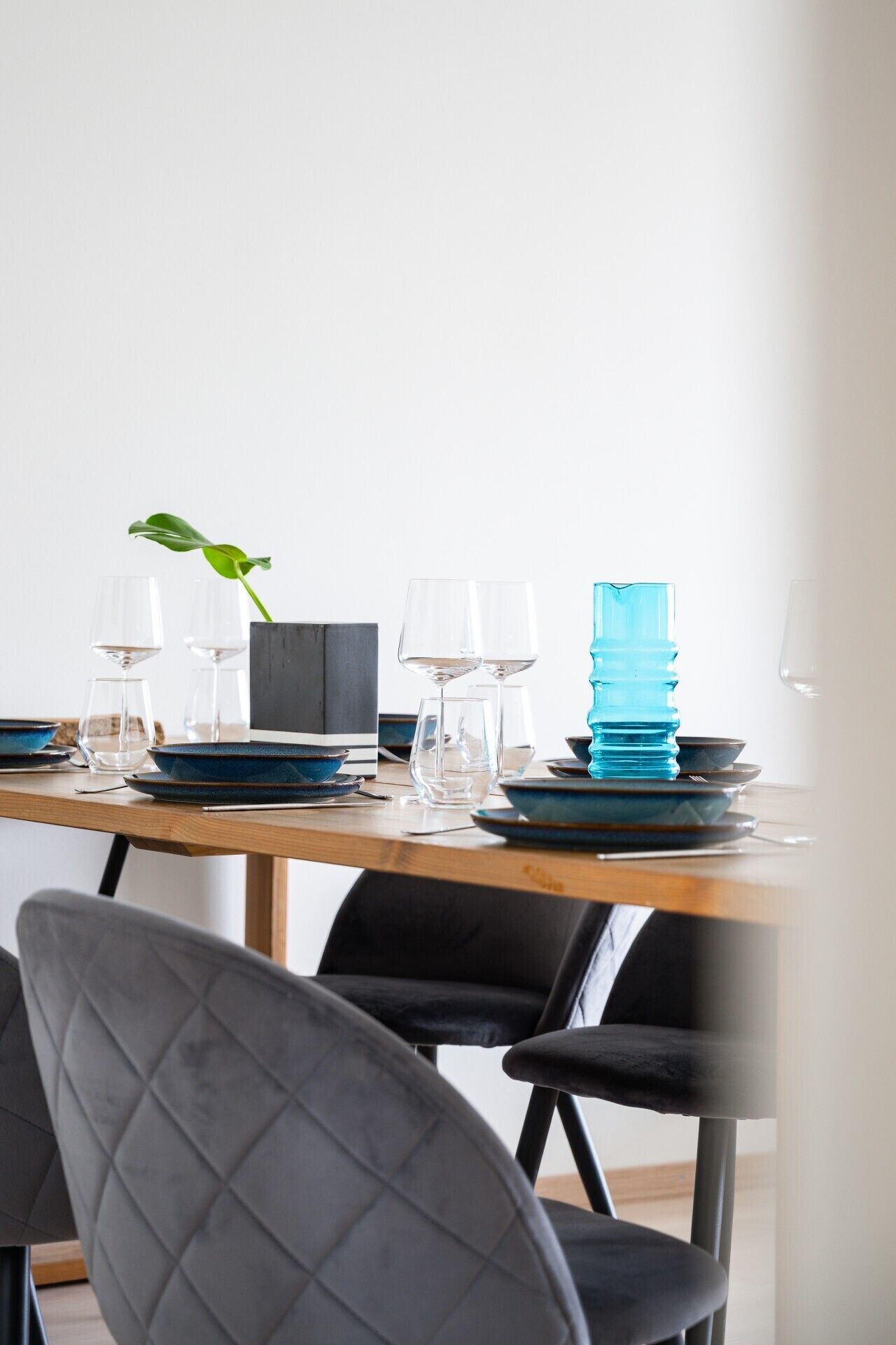 A dining table set with plates, glasses, and a blue water bottle.