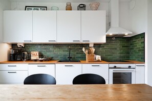 A modern kitchen with white cabinets, a green tiled backsplash, a wooden countertop, and a built-in oven. - Arctic River View Flat By Lapland Host (Rovaniemi)