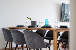 A dining table with chairs, a plant, and a blue vase. - Arctic River View Flat By Lapland Host (Rovaniemi)