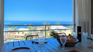 A table set for dining with a view of the ocean, a bowl of fruit, and a bottle of wine. - Vrbo Property (Saint-Paul)