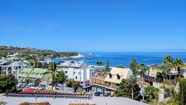 A coastal town with buildings, a beach, and the ocean. - Vrbo Property (Saint-Paul)