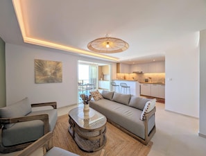 Una sala moderna con sofá, sillones, una mesa de centro y un comedor con sillas y una mesa.