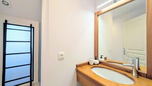 A bathroom with a wooden vanity, a large mirror, and a towel rack. - Vrbo Property (Saint-Paul)