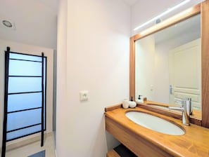 Un baño con tocador de madera, un espejo grande y un perchero para toallas.