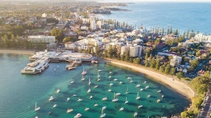 An aerial view of a coastal city with a marina, buildings, and clear blue waters. - KozyGuru | Manly | Serene Coastal House Retreat (Manly)