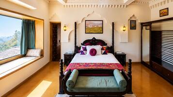 A bedroom with a large bed, a window with curtains, a ceiling fan, and a painting on the wall.
