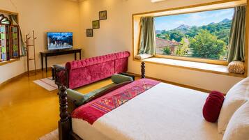 Una habitación de hotel con cama, ventana con vistas, televisor y escritorio.