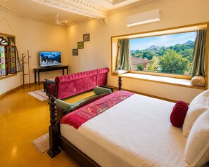 A hotel room with a bed, a window with a view, a television, and a desk.
