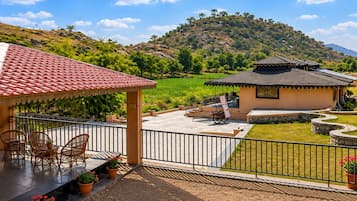 Un hotel con patio, mobiliario exterior y vistas a un paisaje montañoso.