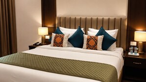 Habitació d'hotel amb un llit gran, dues taules de nit i un capçal amb il·luminació integrada.