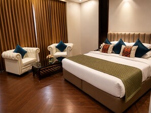 A hotel room with a large bed, two armchairs, a small table with a vase, and a curtain. - Moksha Resort and Spa  (Kapur Pind)