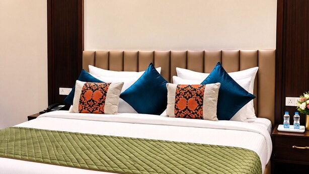 A hotel room with a bed, a nightstand, and a wall-mounted light. - Moksha Resort and Spa (Jalandhar)