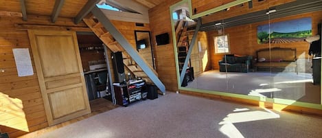 Un interior de madera con una escalera, un muro espejado y un piso alfombrado.
