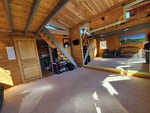 A wooden interior with a staircase, a mirrored wall, and a carpeted floor.