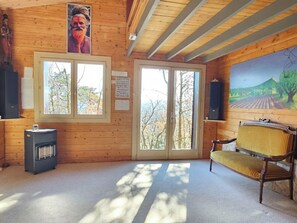 Een kamer met houten wanden en een groot raam, een bankje en een verwarming.