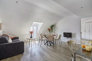 A modern loft apartment with a dining area, a sofa, and a TV. - Superbe Apartment Arc de Triomphe/champs Elysees (Paris)