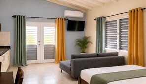 A hotel room with a sofa, a bed, a TV, and a potted plant. - Cozy Curaçao Studio for 4 with AC & Private Patio (willemstad)