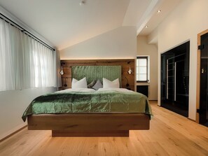 A modern bedroom with a large bed, wooden headboard, and a view of a closet. - Altstadt-Hotel Freiberg - Wellness (Freiberg)