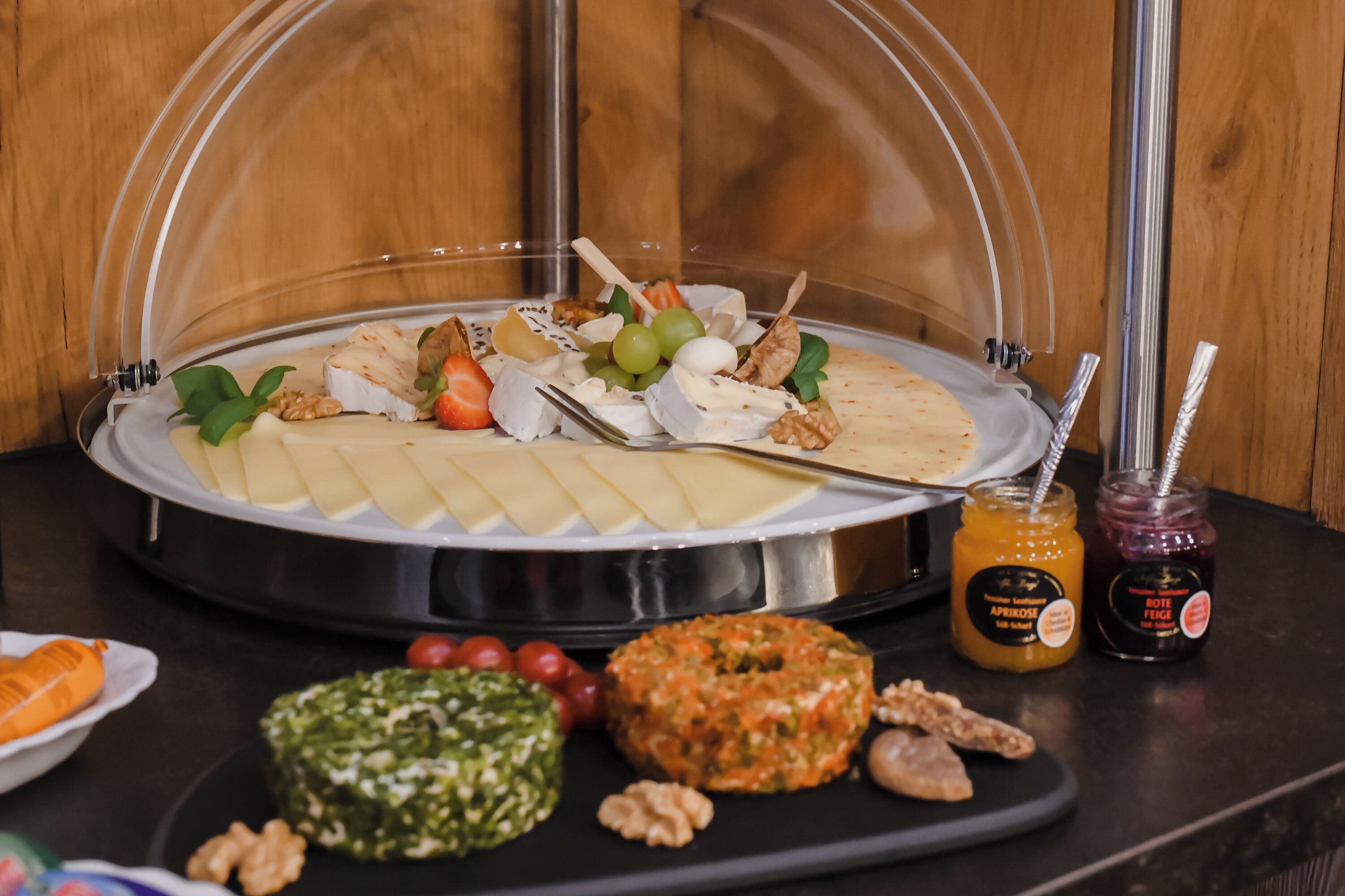 A buffet with a variety of cheeses, fruits, and spreads.