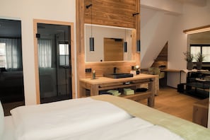 A modern bedroom with a large bed, wooden bedside tables, a built-in sink, and a large mirror. - Altstadt-Hotel Freiberg - Wellness (Freiberg)