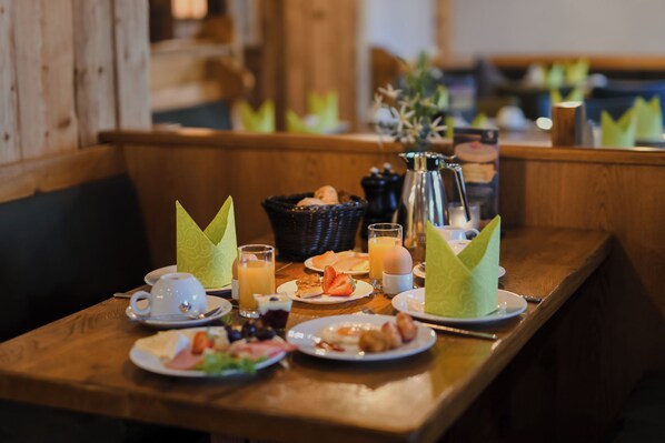 A breakfast table with plates of food, cups, and a basket.
