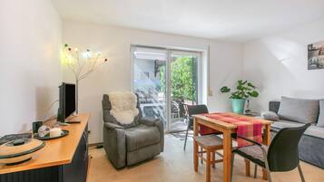 Un salon comprenant un canapé, une table à manger avec des chaises, un téléviseur et une cheminée.