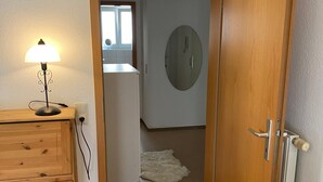 Ein Flur mit einer Holztür, einer weißen Lampe und einem Teppich auf dem Boden.