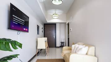 Un salon moderne avec un téléviseur à écran plat fixé au mur, un canapé, une table basse et une petite table avec une chaise.