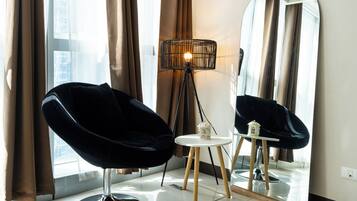Un salon moderne avec un fauteuil noir, une lampe sur pied et un miroir au mur.