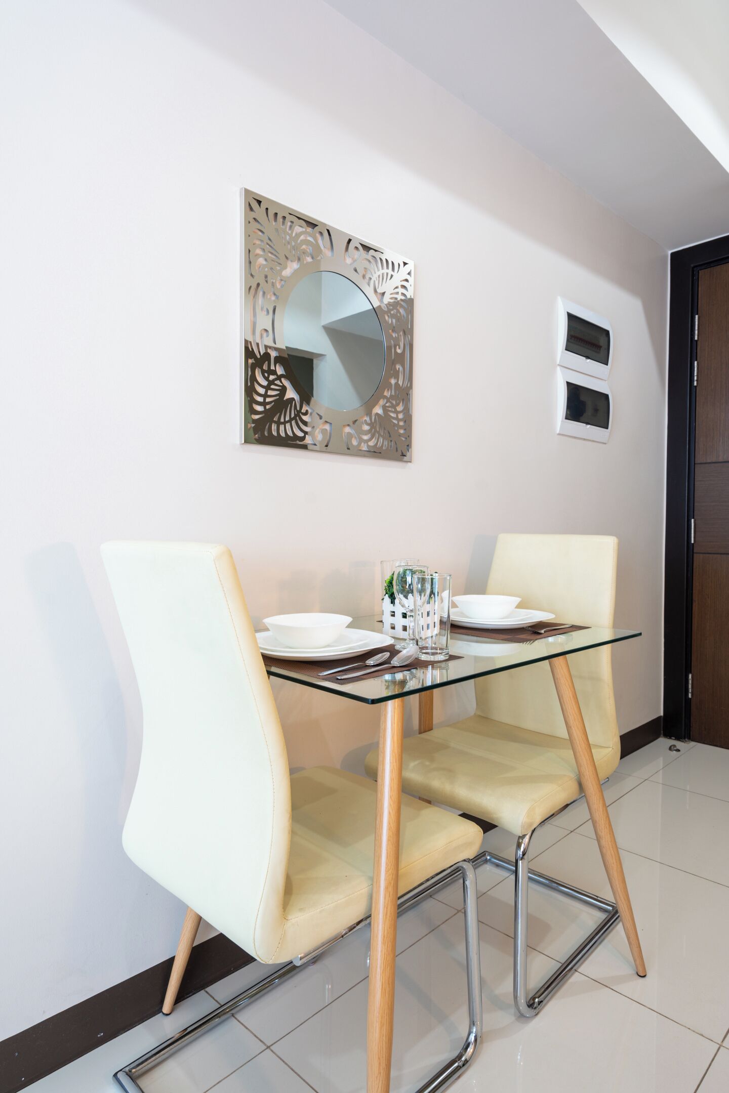 Un coin repas comprenant une table en verre, deux chaises et un élément décoratif mural.