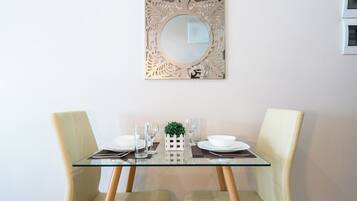 Une table à manger avec des chaises, un plateau en verre et un miroir décoratif placé au-dessus.