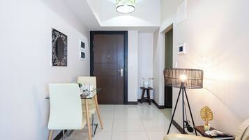 A modern living room with a dining area, a wooden door, a floor lamp, and a small table with a plant.