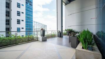 Une vaste terrasse extérieure au design moderne, comprenant un espace salon avec un canapé et plusieurs jardinières agrémentées de plantes vertes.